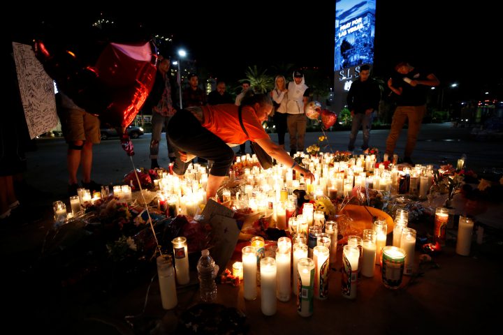 People gather at a vigil on the Las Vegas strip following a mass shooting at the Route 91 Harvest Country Music Festival.