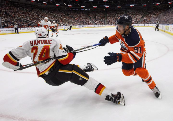 Calgary Flames' Travis Hamonic (24) is knocked down by Edmonton Oilers' Drake Caggiula (91) during second period NHL action in Edmonton, Alta., on Wednesday October 4, 2017. 