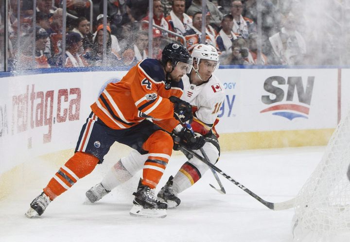 Calgary Flames’ Mikael Backlund (11) and Edmonton Oilers’ Kris Russell (4) battle for the puck during first period NHL action in Edmonton, Alta., on Wednesday October 4, 2017.