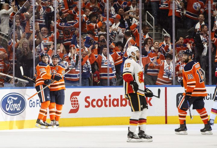Calgary Flames’ Tanner Glass (15) skates past as Edmonton Oilers’ Leon Draisaitl (29), Connor McDavid (97) and Patrick Maroon (19) celebrate a goal during third period NHL action in Edmonton, Alta., on Wednesday October 4, 2017.