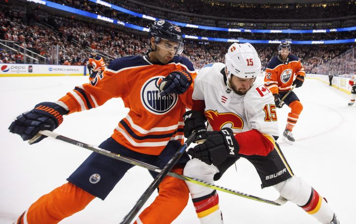 Calgary Flames’ Tanner Glass (15) and Edmonton Oilers’ Darnell Nurse (25) battle in the corner during third period NHL action in Edmonton, Alta., on Wednesday October 4, 2017.