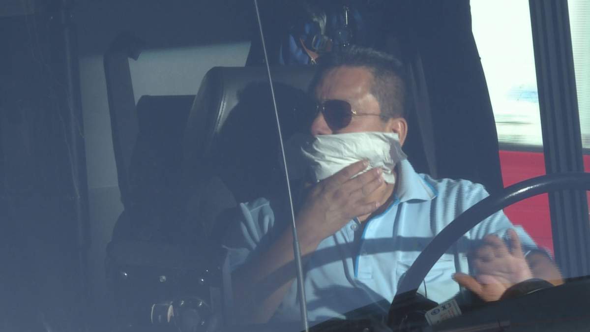 A Montreal bus driver covers his face and honks his horn to support protesters of the province's controversial Bill 62, which would force people to have their faces uncovered to receive services, Friday, Oct. 20, 2017.
