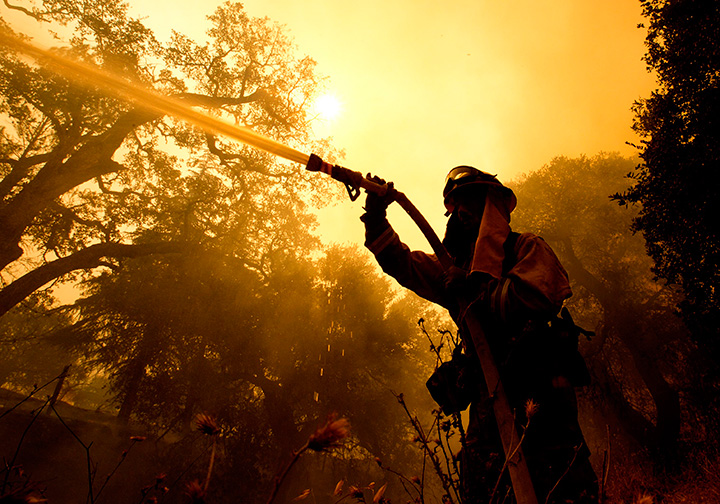 A Napa County firefighter sprays water on a home as he battles flames from a wildfire on Monday, Oct. 9, 2017, in California. 
