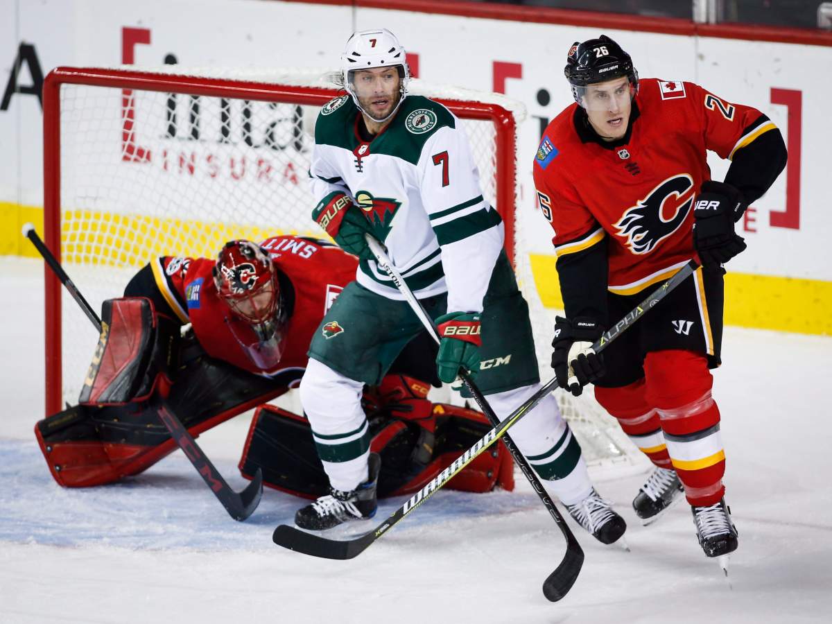 Minnesota Wild's Matt Cullen, looks for a chance to score as Calgary Flames goalie Mike Smith, left, struggles to see past him and teammate Michael Stone during first period NHL hockey action in Calgary, Saturday, Oct. 21, 2017. THE CANADIAN PRESS/Jeff McIntosh.