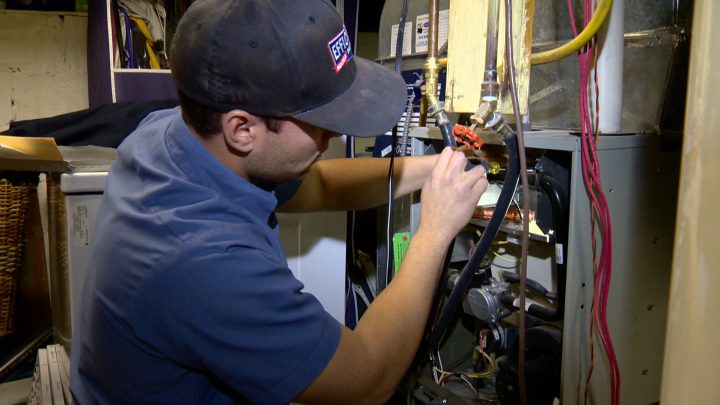 Derek Hautz with Efficiency Heating, Cooling & Fireplaces checks Gail Taman's furnace as part of SaskEnergy's Tune-Up Assistance Program