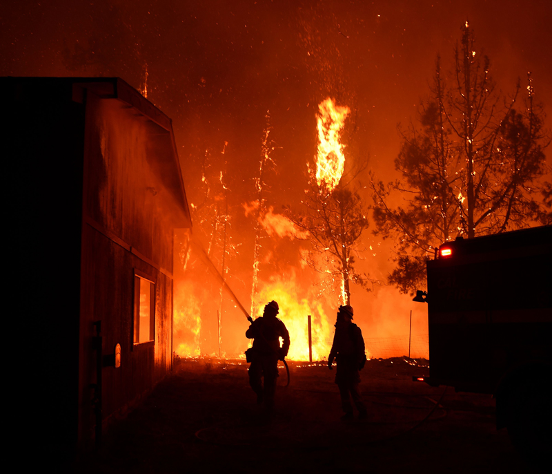 Firefighters douse the Casa Loma fire station as flames approach in the Santa Cruz Mountains near Loma Prieta, California on September 27, 2016. 
The Loma Prieta Fire has charred more than 1,000 acres and burned multiple structures in the area.  / AFP / Josh Edelson        (Photo credit should read JOSH EDELSON/AFP/Getty Images).