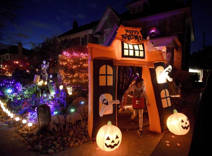A girl trick-or-treats at a decorated home in Ottawa on Halloween, Monday, Oct. 31, 2016. The gleefully shouted phrase of "trick or treat" that children use when they call on houses at Halloween is getting a healthier response in cities across Canada.Instead of candy, little ghosts and goblins are getting passes to go swimming, skating and even skiing.