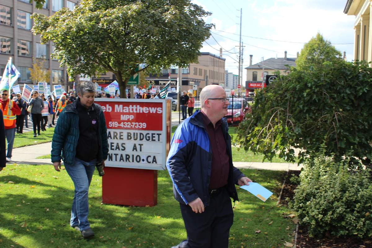 Darryl Bedford, the president of OPSEU local 110, approaches Deb Matthews' constituency office in London with a letter, followed by OPSEU bargaining unit chair, JP Hornick.