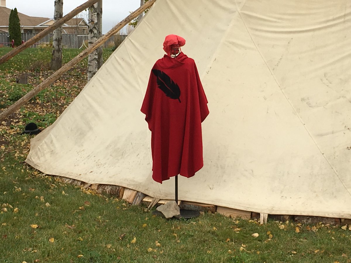 A silhouette stands outside a sacred fire on the Membertou First Nation. The silhouette represent missing and murdered indigenous women and girls. 