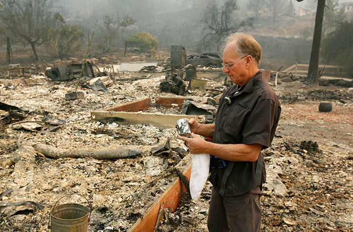 Chuck Rippey looks over a cup found in the burned remains of his parent’s home at the Silverado Resort, Tuesday, Oct. 10, 2017, in Napa, California.