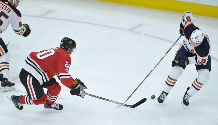 Chicago Blackhawks' Brandon Saad (20) battles Edmonton Oilers' Connor McDavid (97) for a loose puck during the second period of an NHL hockey game Thursday, Oct. 19, 2017, in Chicago. 