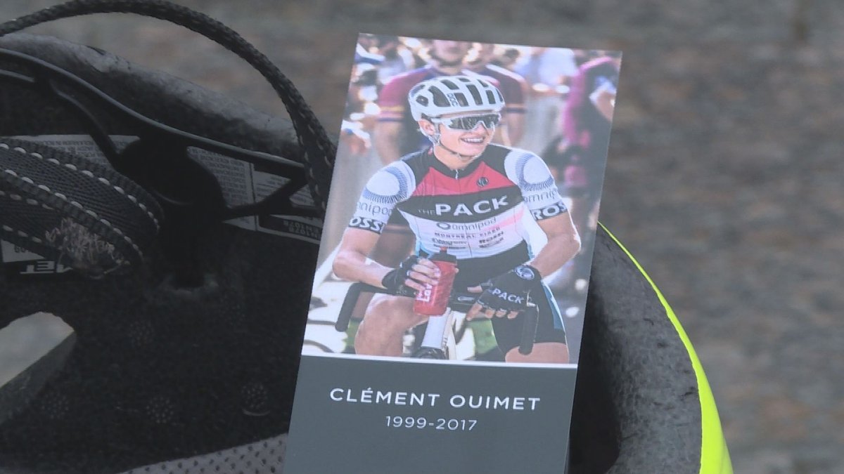 A cyclist holds a bookmark handed out to mourners at memorial for Clement Ouimet, in Montreal, Sunday October 15, 2017. 