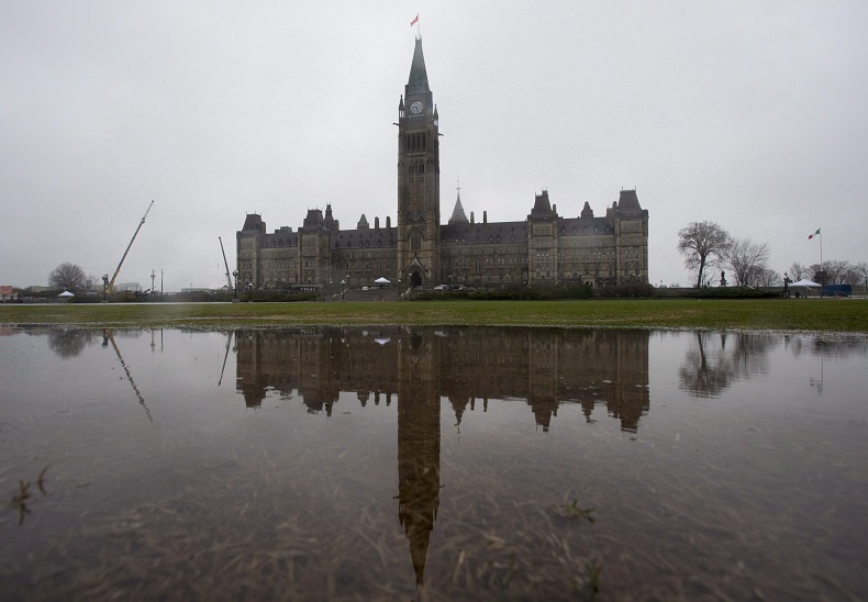 Parliament Hill is reflected in a puddle on the front lawn during a rainstorm in Ottawa in April 2017.