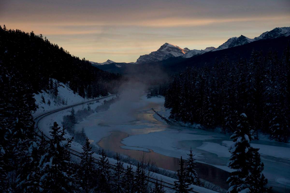 Steam covers off the Bow River as the sun sets on nearby mountain tops near Lake Louise, Alta,