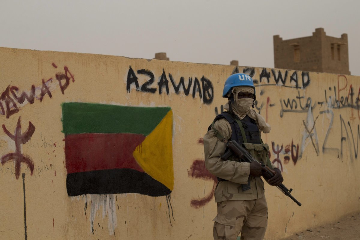 In this Sunday, July, 28, 2013 file photo, a United Nations peacekeeper stands guard at the entrance to a polling station covered in separatist flags and graffiti supporting the creation of the independent state of Azawad, in Kidal, Mali. 