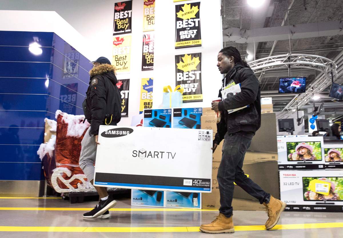 Customers carry a smart TV through a Best Buy store during Black Friday sales in Toronto on Friday, Nov. 27, 2015.