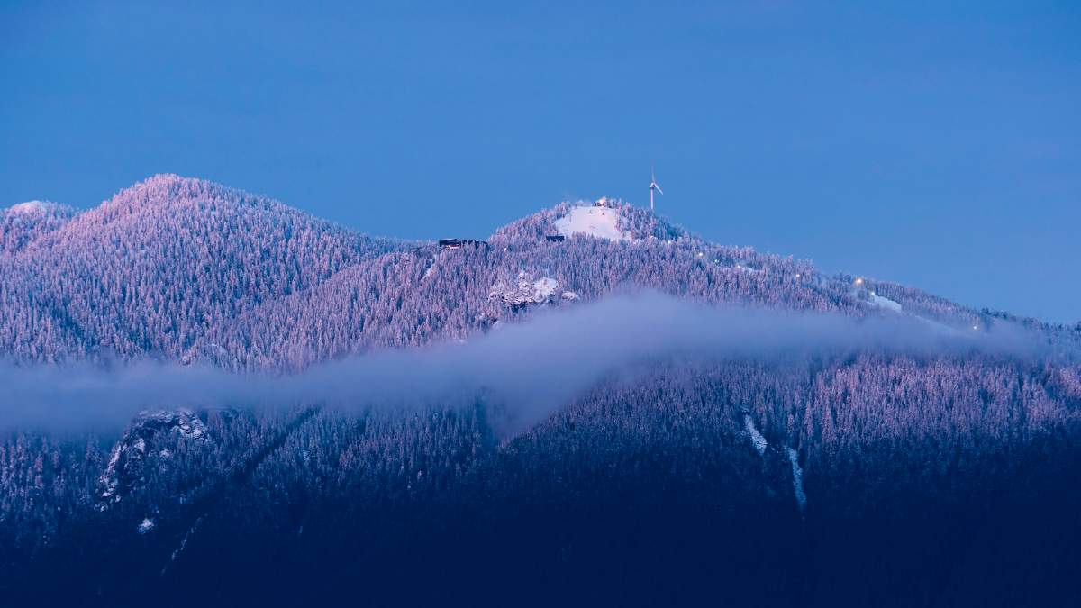 Sunset colours light up fresh snow on the peaks of Vancouver's North Shore Mountains, including the Grouse Mountain ski runs, North Vancouver, B.C., February 2, 2016. 