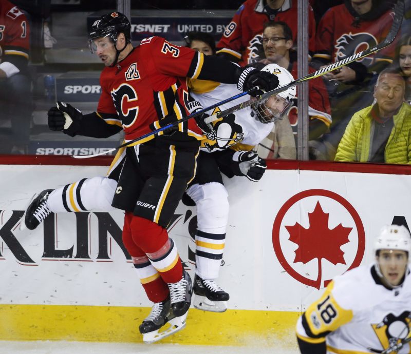 Pittsburgh Penguins' Ian Cole, right, is checked by Calgary Flames' Troy Brouwer during second period NHL hockey action in Calgary, Thursday, Nov. 2, 2017.