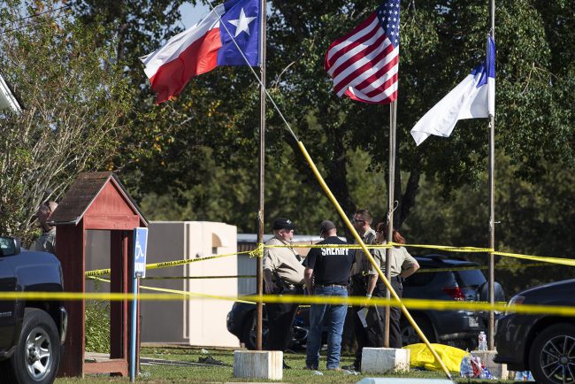 Law enforcement officials stand next to a covered body at the scene of a fatal shooting at the First Baptist Church in Sutherland Springs, Texas, on Sunday, Nov. 5, 2017. (Nick Wagner/Austin American-Statesman via AP).