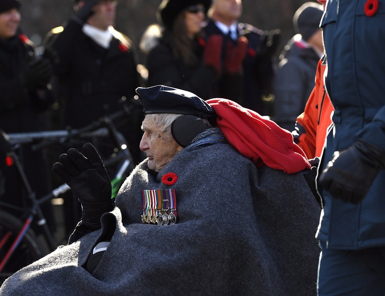 A veteran waves as he participates in the march during the National Remembrance Day Ceremony in Ottawa on Saturday, Nov. 11, 2017. 
