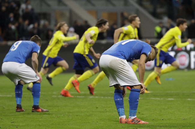 Italian players react to their elimination as Sweden's team celebrates at the end of the World Cup qualifying playoff match between Italy and Sweden at Milan's San Siro stadium on Nov. 13, 2017.
