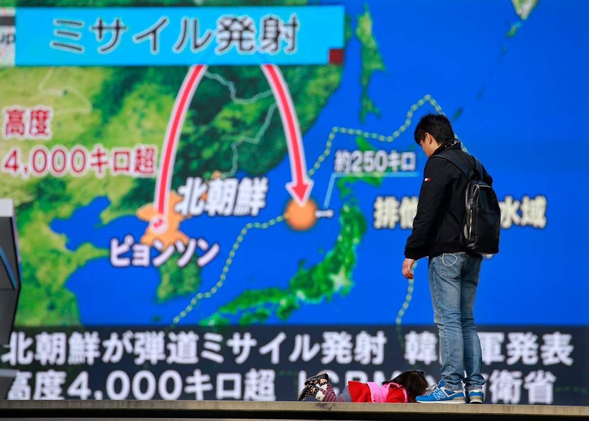 A man stands in front of a huge screen showing TV news program reporting North Korea’s missile launch, in Tokyo, Wednesday.