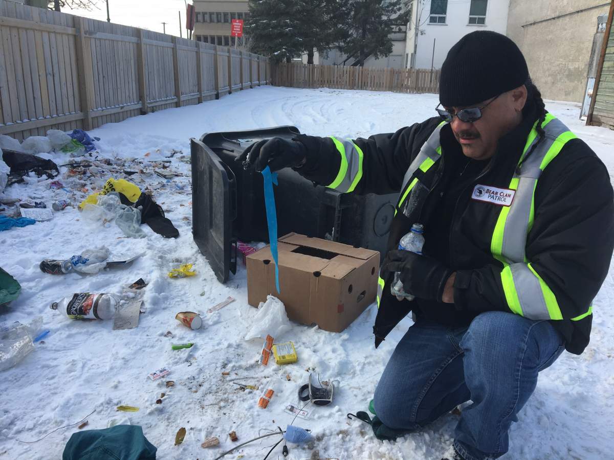 James Favel with the Bear Clan Patrol digs through garbage on the ground to remove needles.