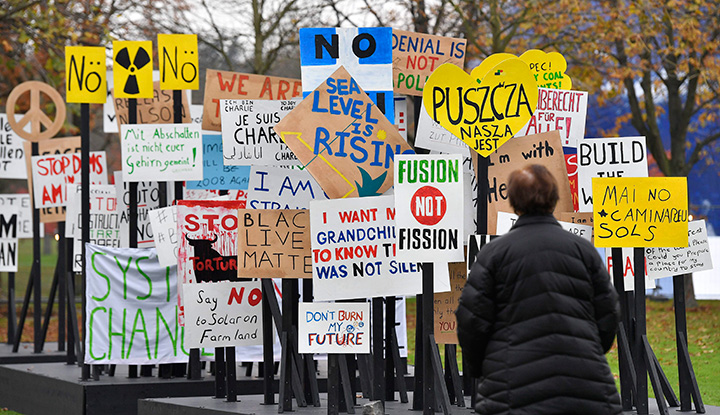 A visitor watches protest banners outside the COP 23 Fiji UN Climate Change Conference in Bonn, Germany, Monday, Nov. 6, 2017. 