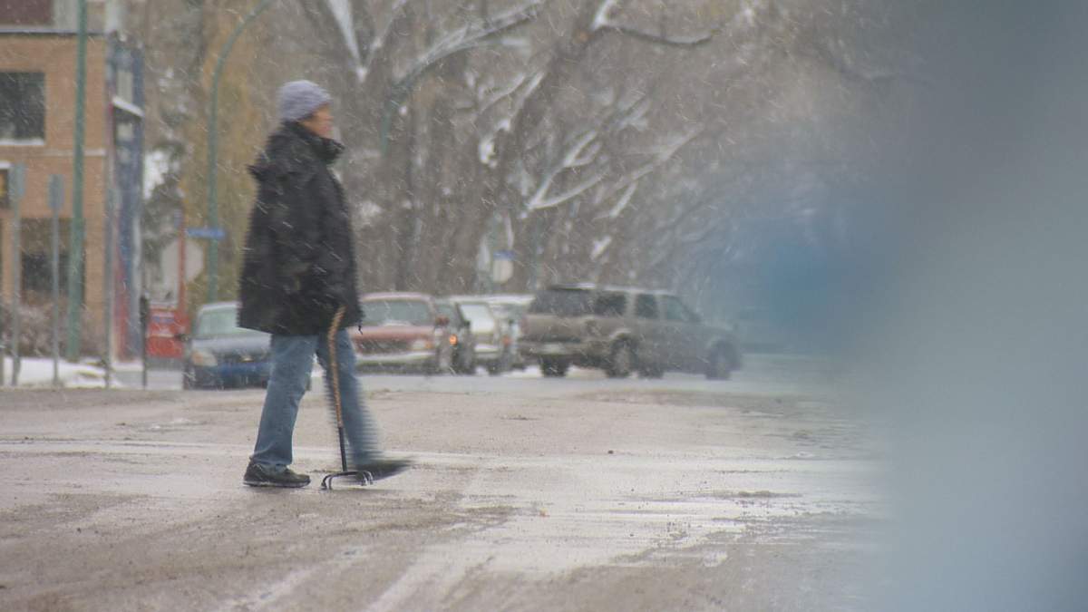 A man crosses the road on a snowy Regina day. 
