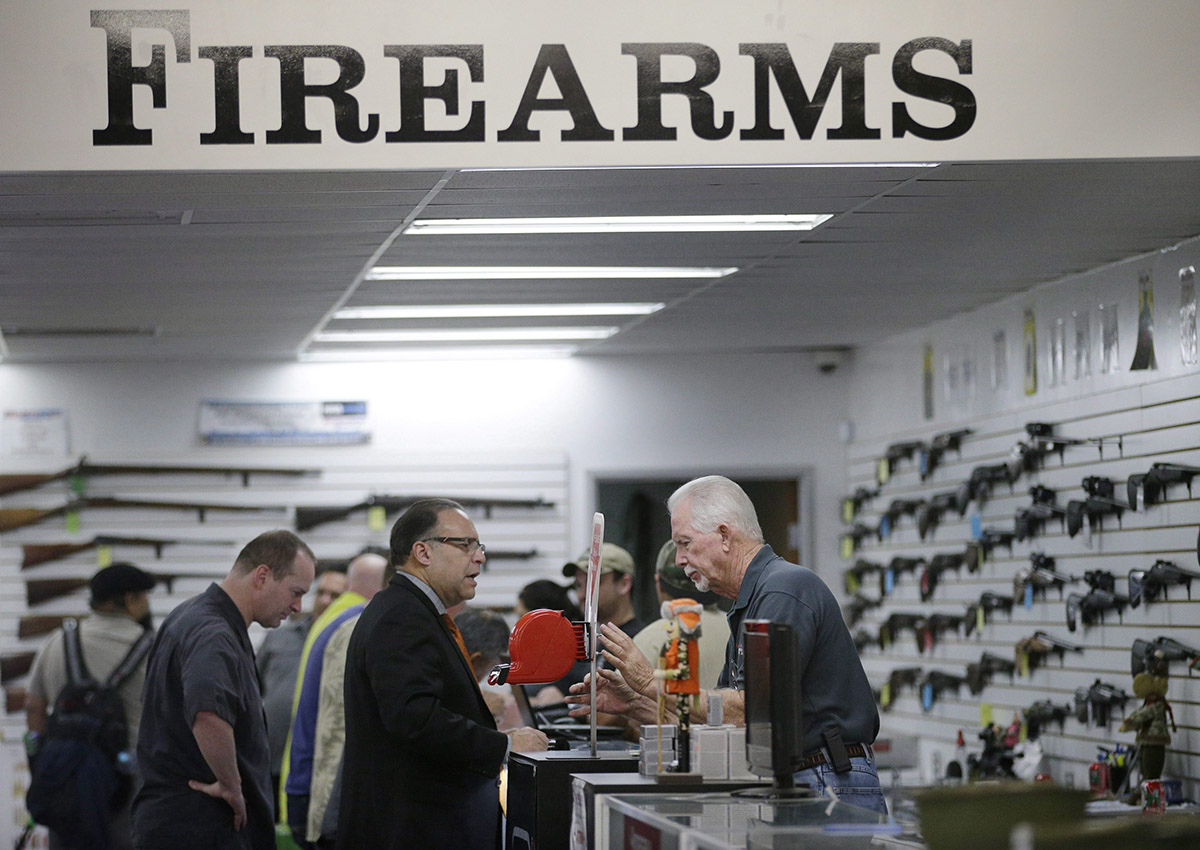 In this Dec. 9, 2015, file photo, sales associate Mike Conway, right, shows Paul Angulo guns at Bullseye Sport gun shop in Riverside, Calif. 