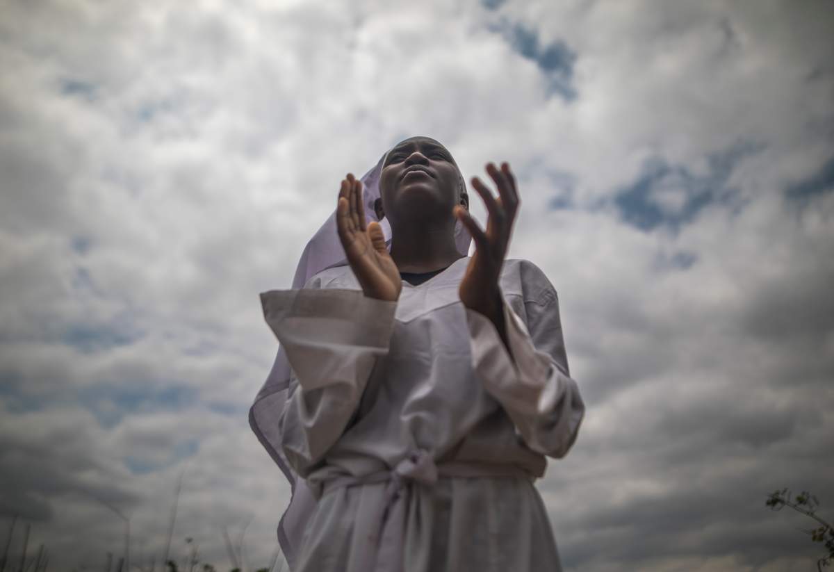A Zimbabwean woman leads a prayer outdoors in in Harare Zimbabwe, on 19 November a day after huge crowds rallied peacefully in the capital for 93-year-old President Robert Mugabe to step down (Photo by Belal Khaled/NurPhoto via Getty Images)