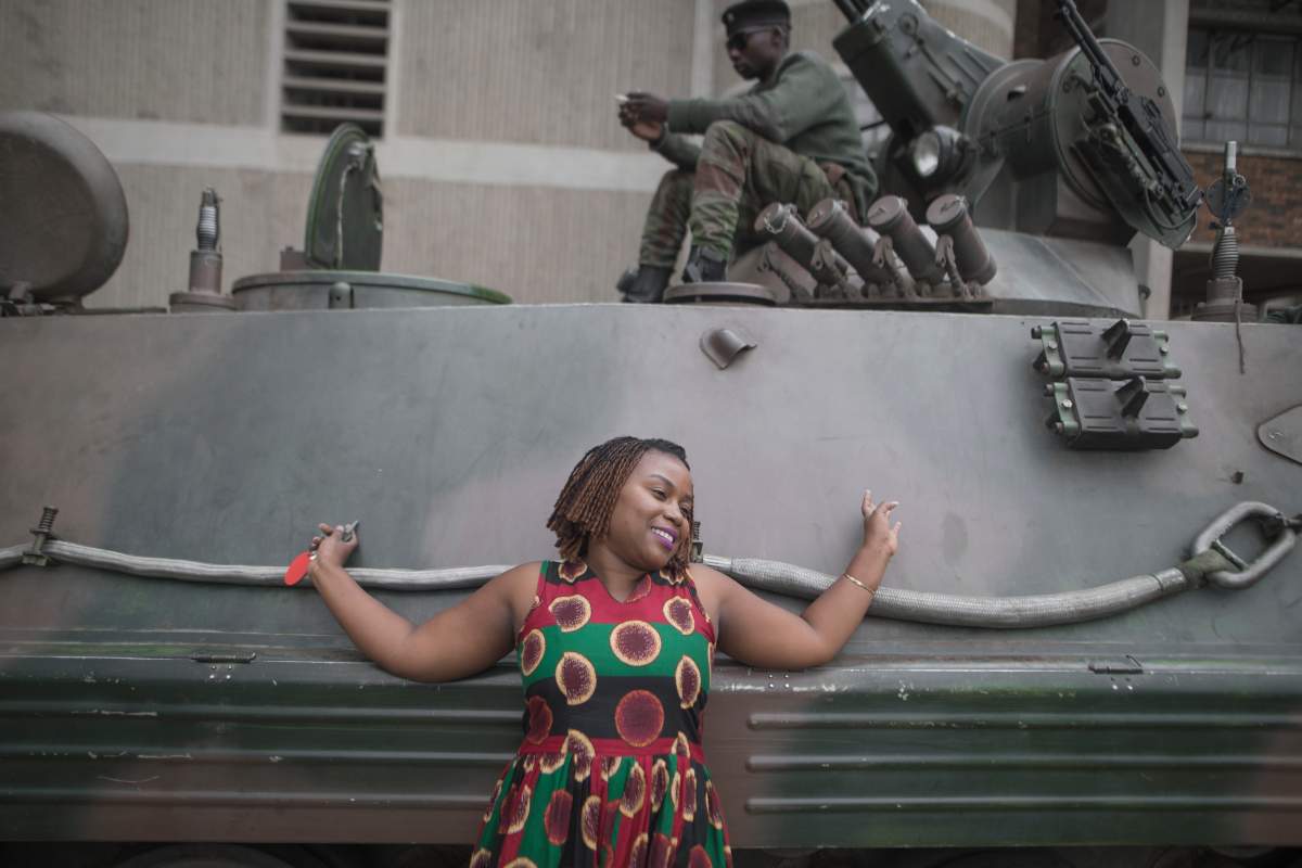 An African woman takes pictures with one of the armored vehicles in the streets of the capital Harare, Zimbabwe, on 19 November 2017, a day after huge crowds rallied peacefully in the capital for 93-year-old President Robert Mugabe to step down. (Photo by Belal Khaled/NurPhoto via Getty Images)