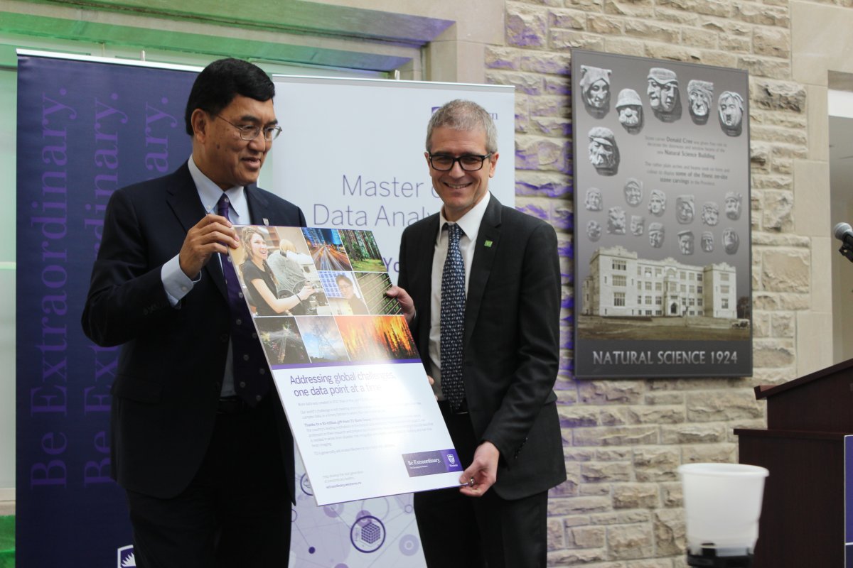 Western University president Amit Chakma presents TD Bank Group's Senior Vice President of Enterprise Data and Analytics, Christian Nelissen with a plaque of an advertisement.