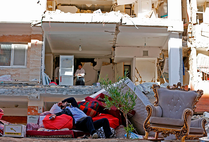 A man rests as he lies atop of salvaged mattresses and items outside damaged buildings in the town of Sarpol-e Zahab, on November 14, 2017, following a 7.3-magnitude earthquake.