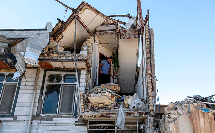 A man looks through a damaged stairwell of a building in the town of Sarpol-e Zahab on November 14, 2017, following a 7.3-magnitude earthquake.