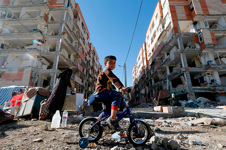 An Iranian boy rides a bicycle through the rubble past damaged buildings in the town of Sarpol-e Zahab on November 14, 2017, following a 7.3-magnitude earthquake.