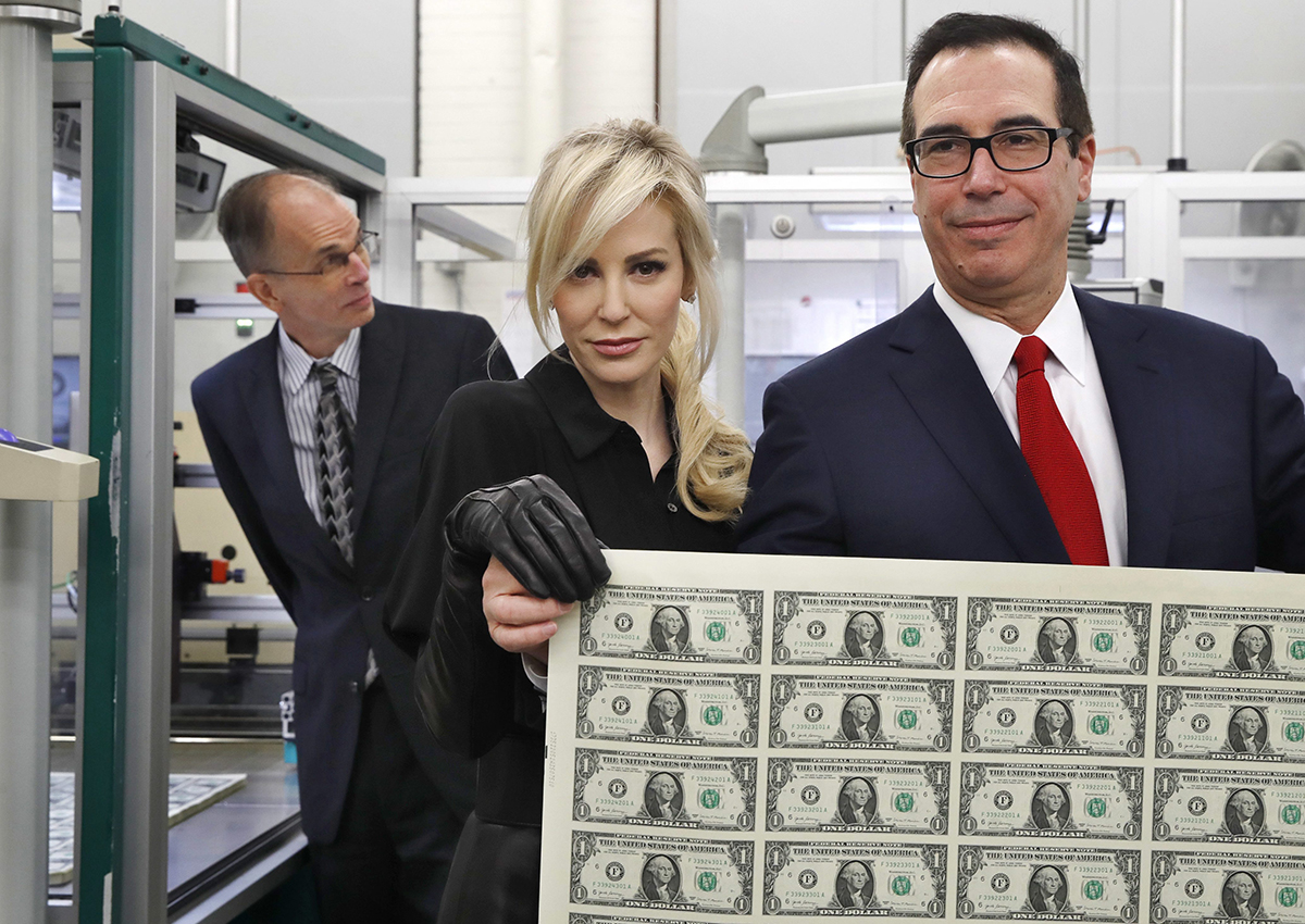 Treasury Secretary Steven Mnuchin, right, and his wife Louise Linton, hold up a sheet of new $1 bills.