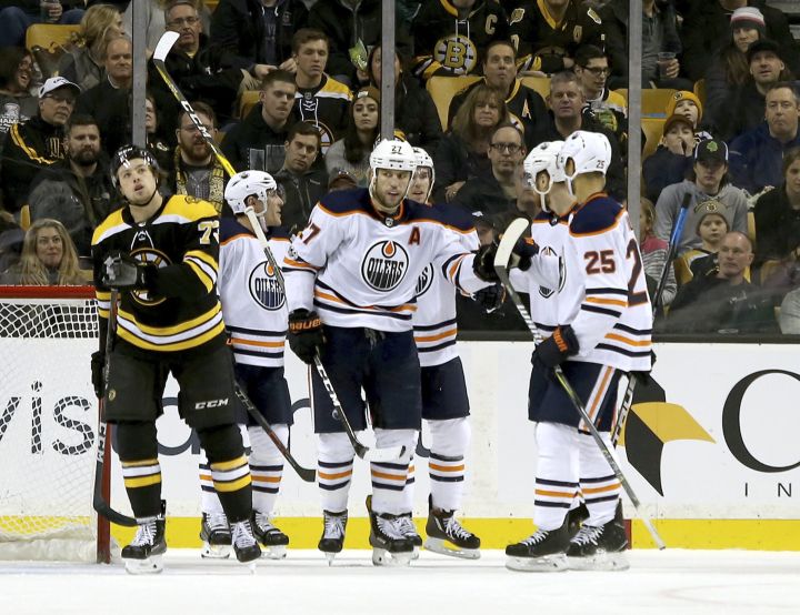 Edmonton Oilers left wing Milan Lucic (27) is congratulated by teammates after scoring a goal as Boston Bruins defenseman Charlie McAvoy (73) looks us at the replay during the second period of an NHL hockey game in Boston, Sunday, Nov. 26, 2017. 