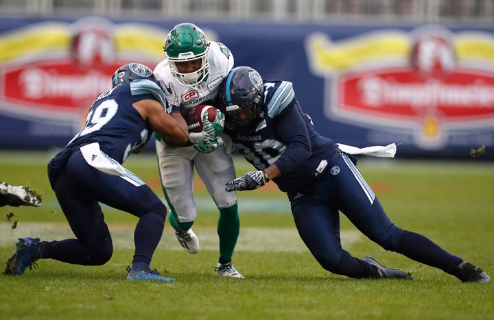Saskatchewan Roughriders wide receiver Marcus Thigpen is stopped by a pair of Toronto Argonauts defenders during CFL Eastern final on Sunday. 