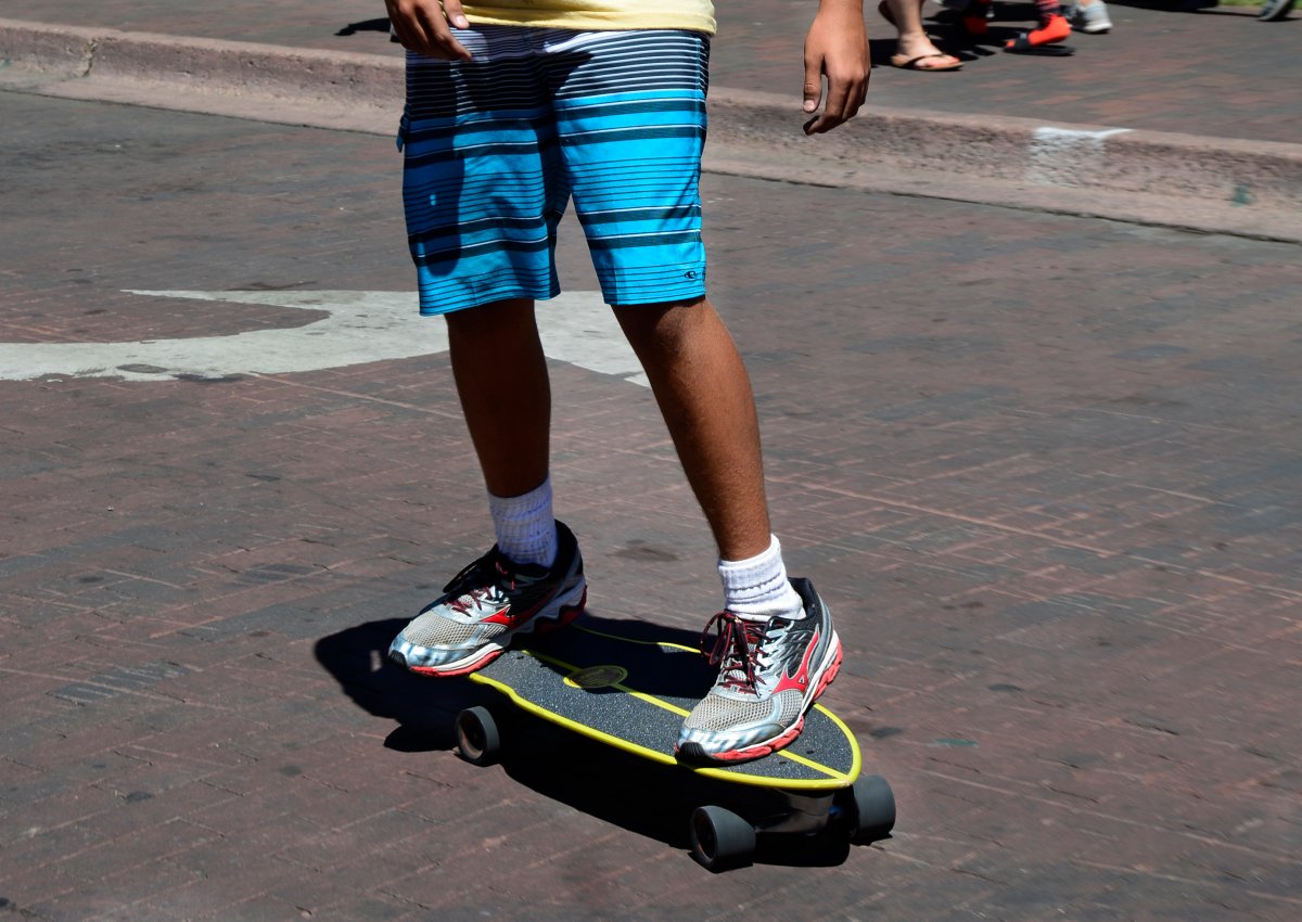  A teenage boy rides his skateboard along a street bordering the historic Plaza in Santa Fe, New Mexico. 