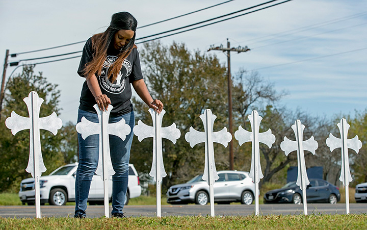 A woman prays over two of the 26 crosses erected in memory of the people killed in a shooting in Sutherland Springs, Texas on Monday, Nov. 6, 2017.