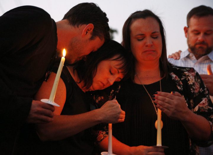From left, Ryan Donato, Heather Barclay and her sister Tracy Gyurina grieve at a candlelight vigil for Nicol Kimura, a victim of the Las Vegas mass shooting, at Sierra Vista Elementary School in Placentia, Calif., Sunday, Oct. 8, 2017. 