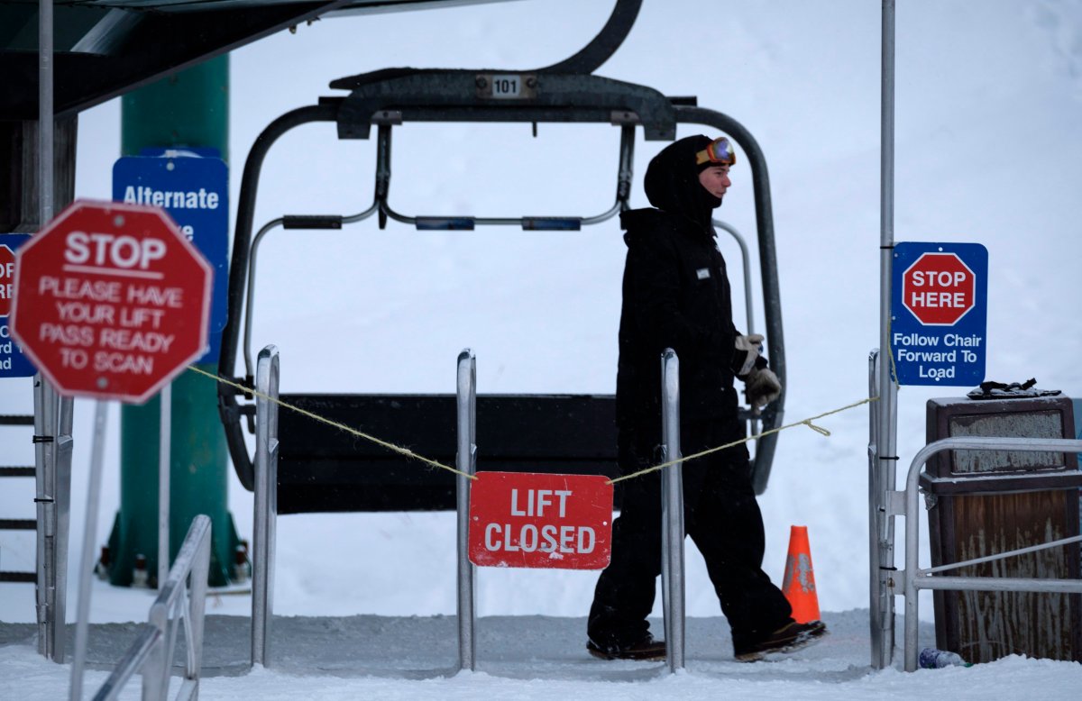 A chair lift worker walks past a closed lift after a power failure shut down all operations at the women's World Cup downhill ski race at Lake Louise, Alta., Saturday, Dec. 2, 2017.