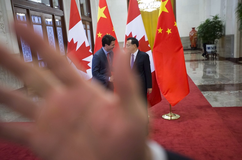 A security guard attempts to block a photographer as a picture is taken of Prime Minister Justin Trudeau being greeted by Chinese Premier Li Keqiang at the Great Hall of the People in Beijing, on Monday, Dec. 4, 2017.