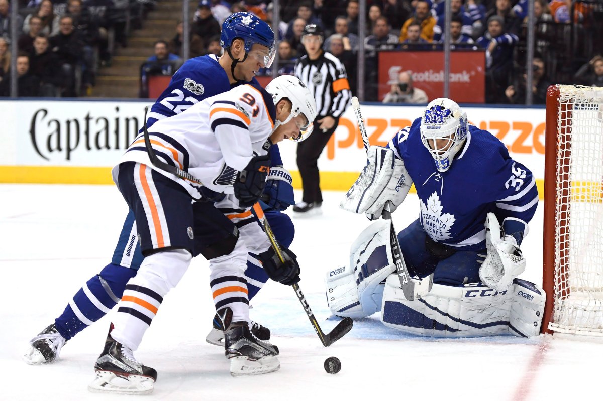 Edmonton Oilers left wing Drake Caggiula (91) drives to the net under pressure from Toronto Maple Leafs defenceman Nikita Zaitsev (22) as goalie Curtis McElhinney (35) watches the puck during first period NHL hockey action in Toronto on Sunday, Dec. 10, 2017.