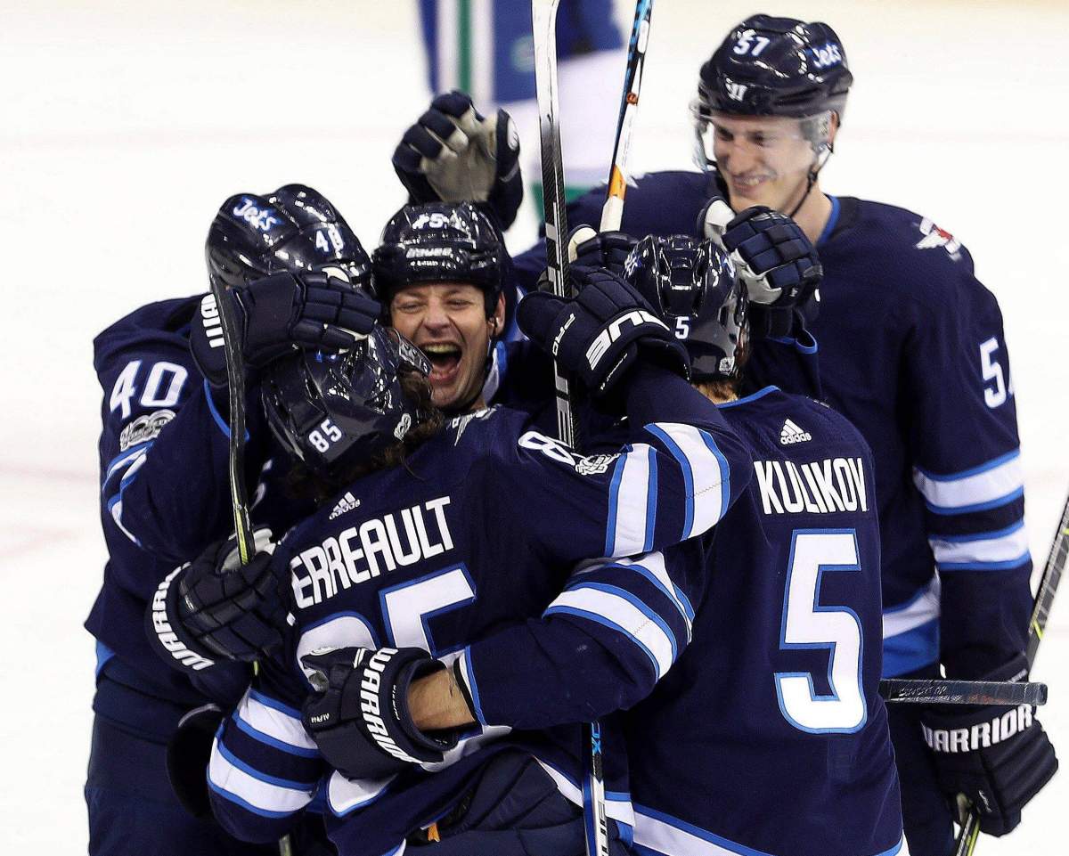 Winnipeg Jets' Matt Hendricks (15), middle, celebrates with Joel Armia (40), Mathieu Perreault (85), Dmitry Kulikov (5) and Tyler Myers (57) after Perreault's goal during third period NHL hockey action against the Vancouver Canucks, in Winnipeg, Monday, December 11, 2017. THE CANADIAN PRESS/Trevor Hagan.