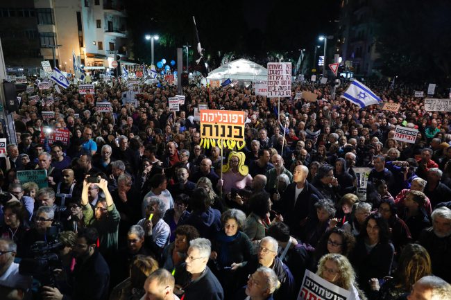Israeli protestors hold signs during the weekly protest march called 'march of shame' against government corruption in Tel Aviv, Israel, Dec. 16, 2017. 