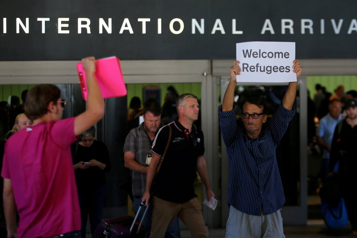 Retired engineer John Wider, 59, is greeted by a supporter of U.S. President Donald Trump as he holds up a sign reading "Welcome Refugees" at the international arrivals terminal at Los Angeles International Airport.