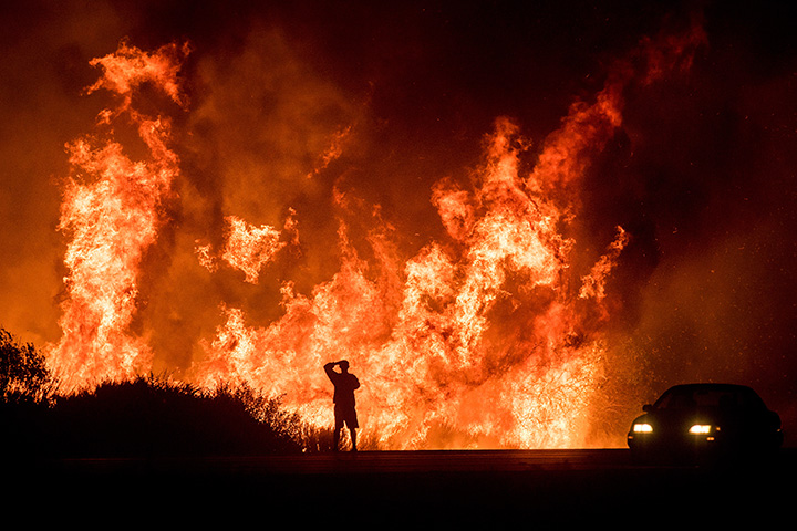 A motorists on Highway 101 watches flames from the Thomas fire leap above the roadway north of Ventura, Calif., on Wednesday, Dec. 6, 2017.