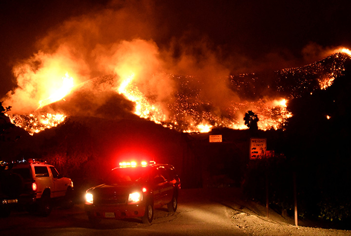 Emergency crews block a roadway as flames spread from a Santa Ana wind-driven brush fire dubbed the Thomas Fire near Ventura, California, December 5, 2017.